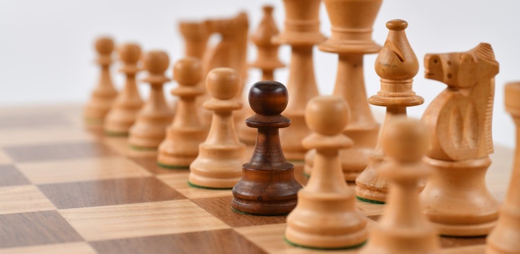 Chess pieces, with a black pawn standing out from the white