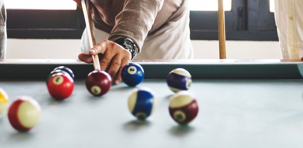 Billiard table with player leaning over, ready to make a shot. Five balls are on the table.